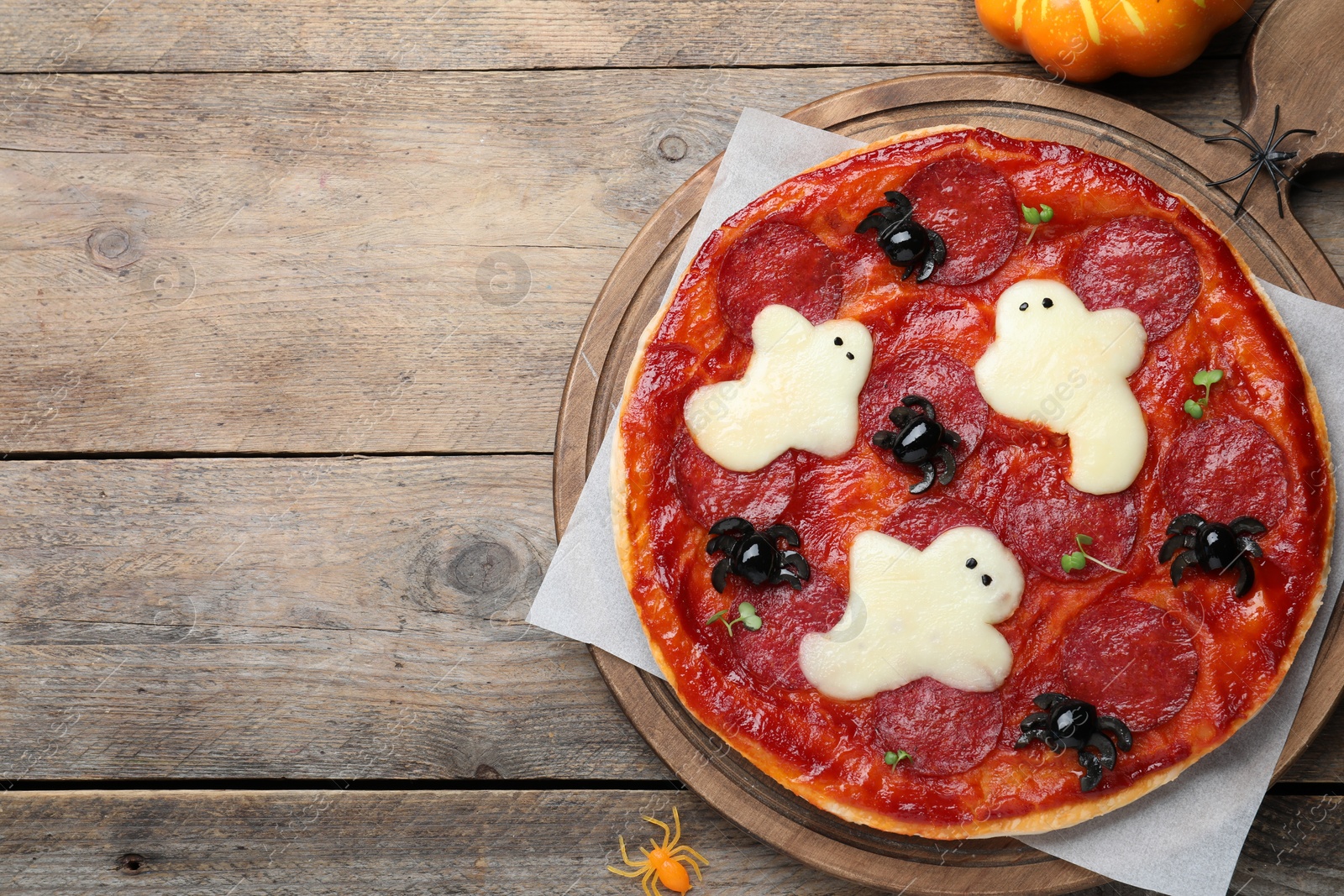 Photo of Cute Halloween pizza with ghosts and spiders served on wooden table, flat lay. Space for text