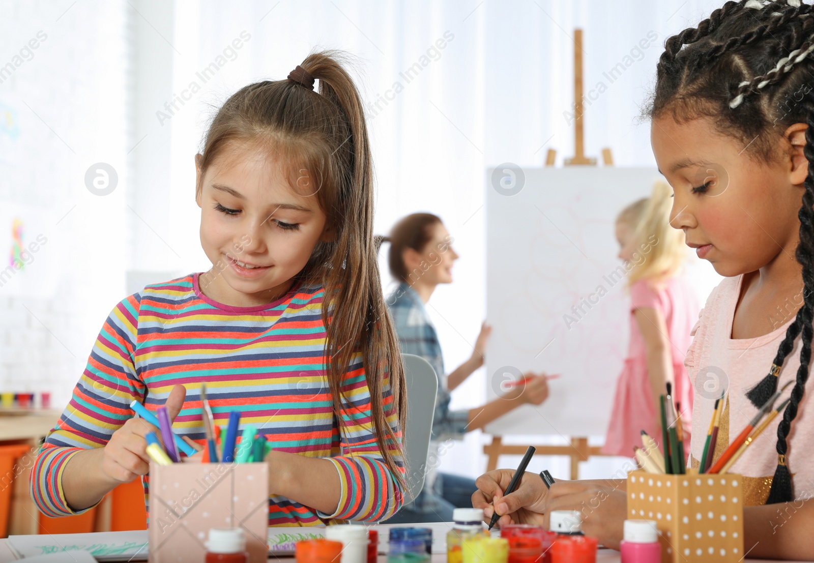 Photo of Cute little children drawing at painting lesson indoors