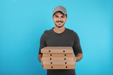 Young courier with pizza boxes on color background. Food delivery service