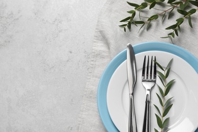 Photo of Stylish setting with cutlery and eucalyptus leaves on light grey table, flat lay. Space for text