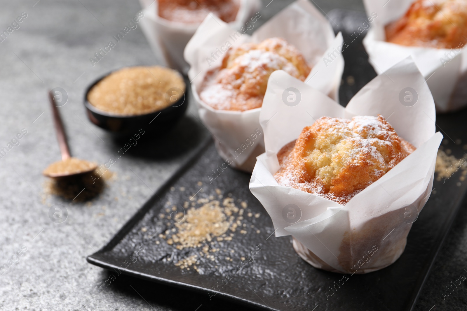 Photo of Delicious muffins with powdered sugar on grey table, closeup