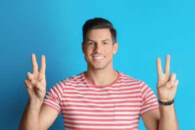 Photo of Man showing number four with his hands on light blue background