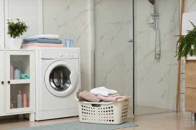 Photo of Basket with laundry and washing machine in bathroom