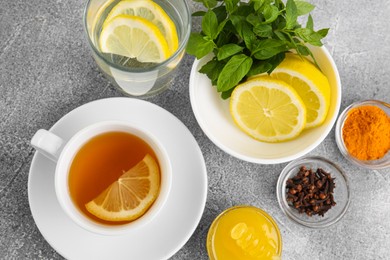 Cup with delicious immunity boosting tea and ingredients on grey table, flat lay