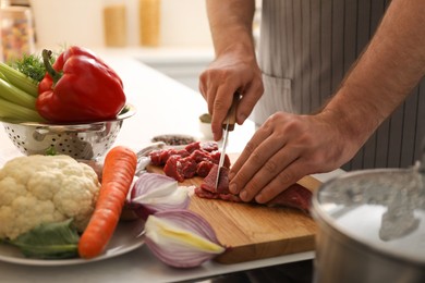 Photo of Man cutting meat to make bouillon in kitchen, closeup. Homemade recipe