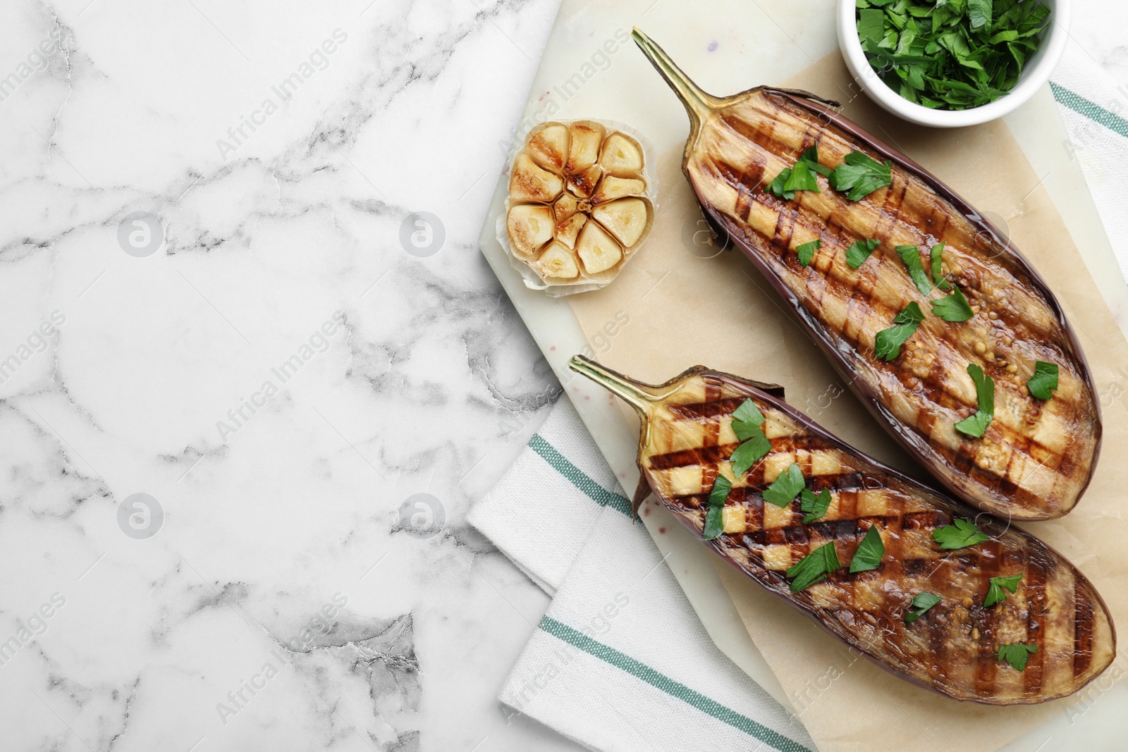 Photo of Delicious grilled eggplant halves with parsley on white marble table, flat lay. Space for text