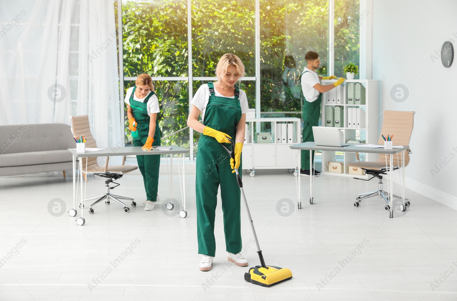 Photo of Team of janitors in uniform cleaning office