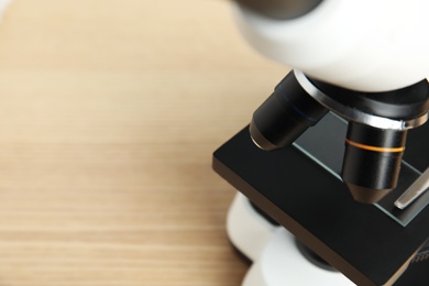 Closeup view of modern microscope on wooden table, space for text. Medical equipment