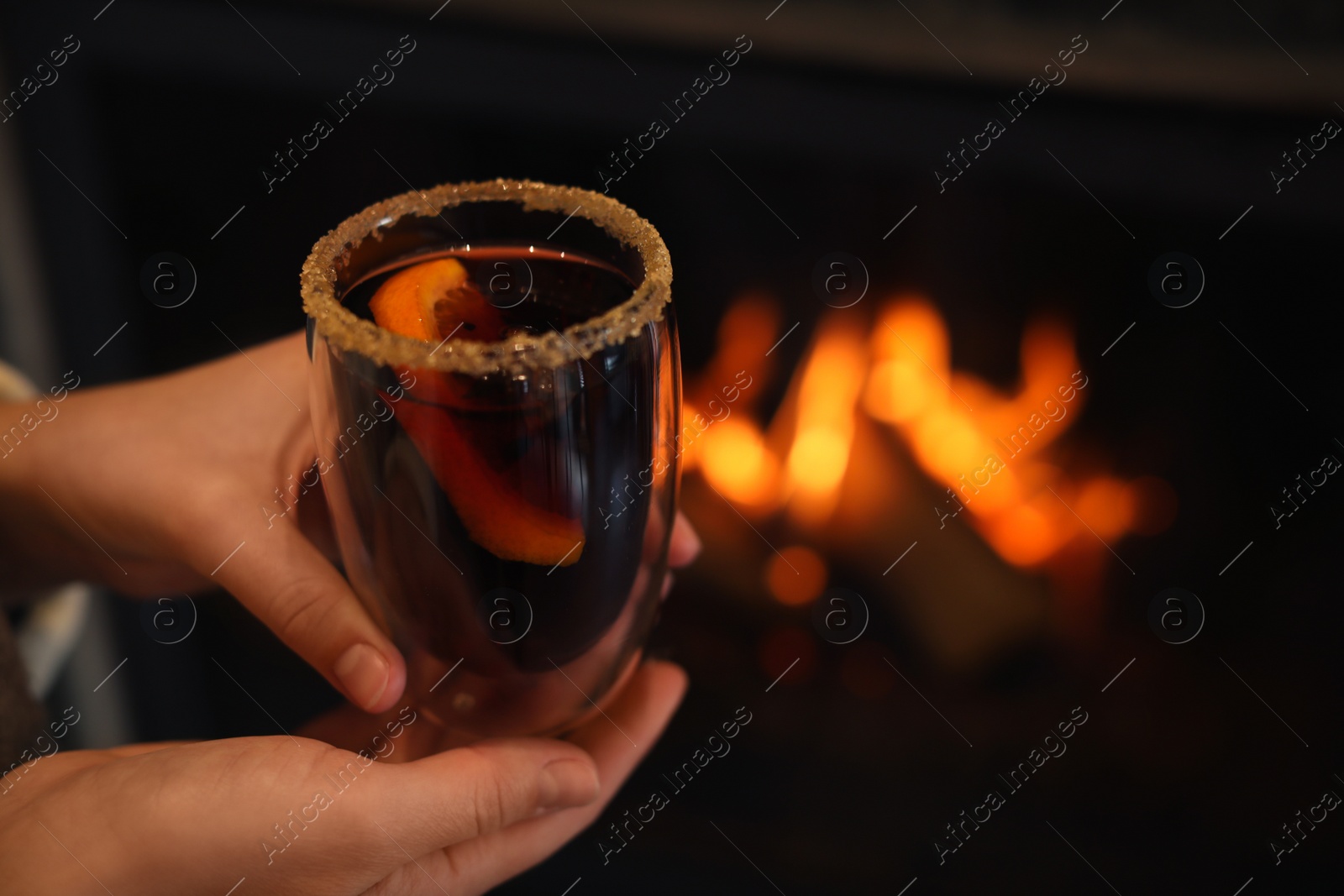 Photo of Woman with tasty mulled wine near fireplace indoors, closeup