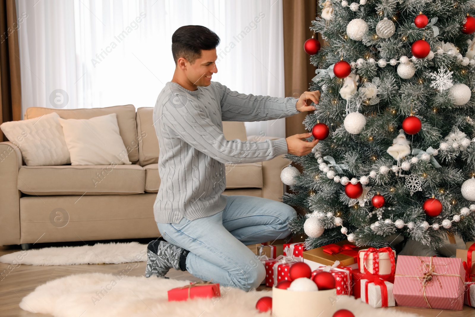 Photo of Handsome man decorating Christmas tree at home