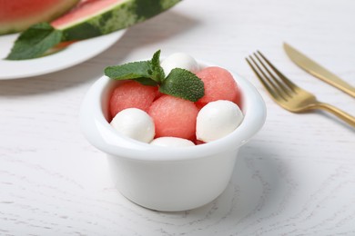 Photo of Delicious salad with watermelon balls, mint and mozzarella served on white wooden table, closeup