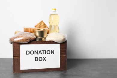 Donation box with food on wooden table against white background