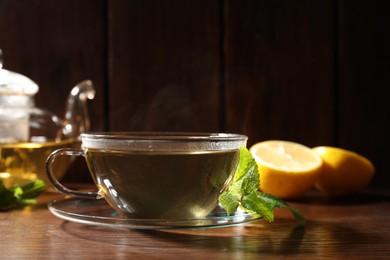 Photo of Cup of aromatic herbal tea and mint on wooden table