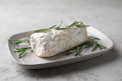 Photo of Delicious fresh goat cheese with rosemary on light grey table
