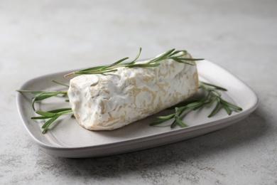 Delicious fresh goat cheese with rosemary on light grey table