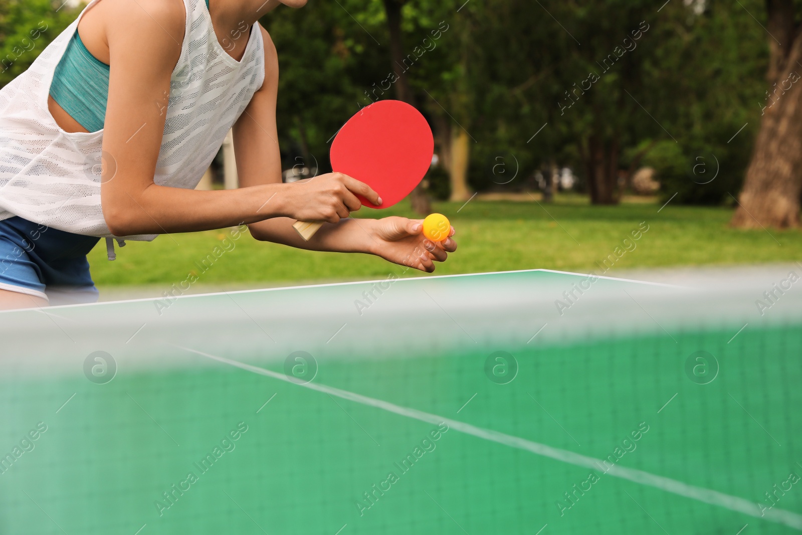 Photo of Woman playing ping pong outdoors on summer day, closeup