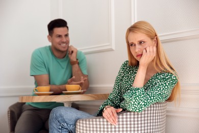 Photo of Displeased young woman and happy man during first date in cafe