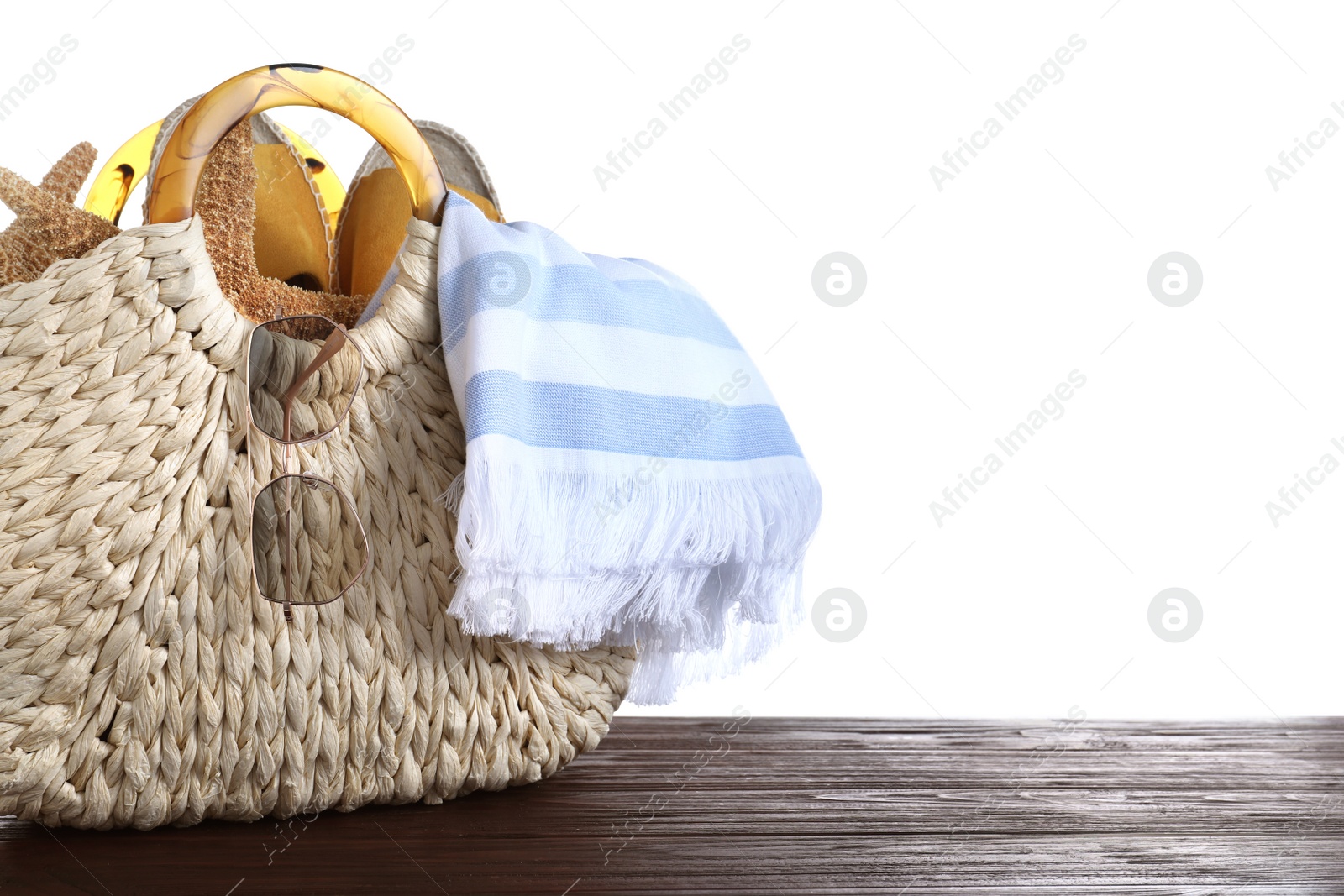 Photo of Bag with different beach objects on wooden table against white background. Space for text