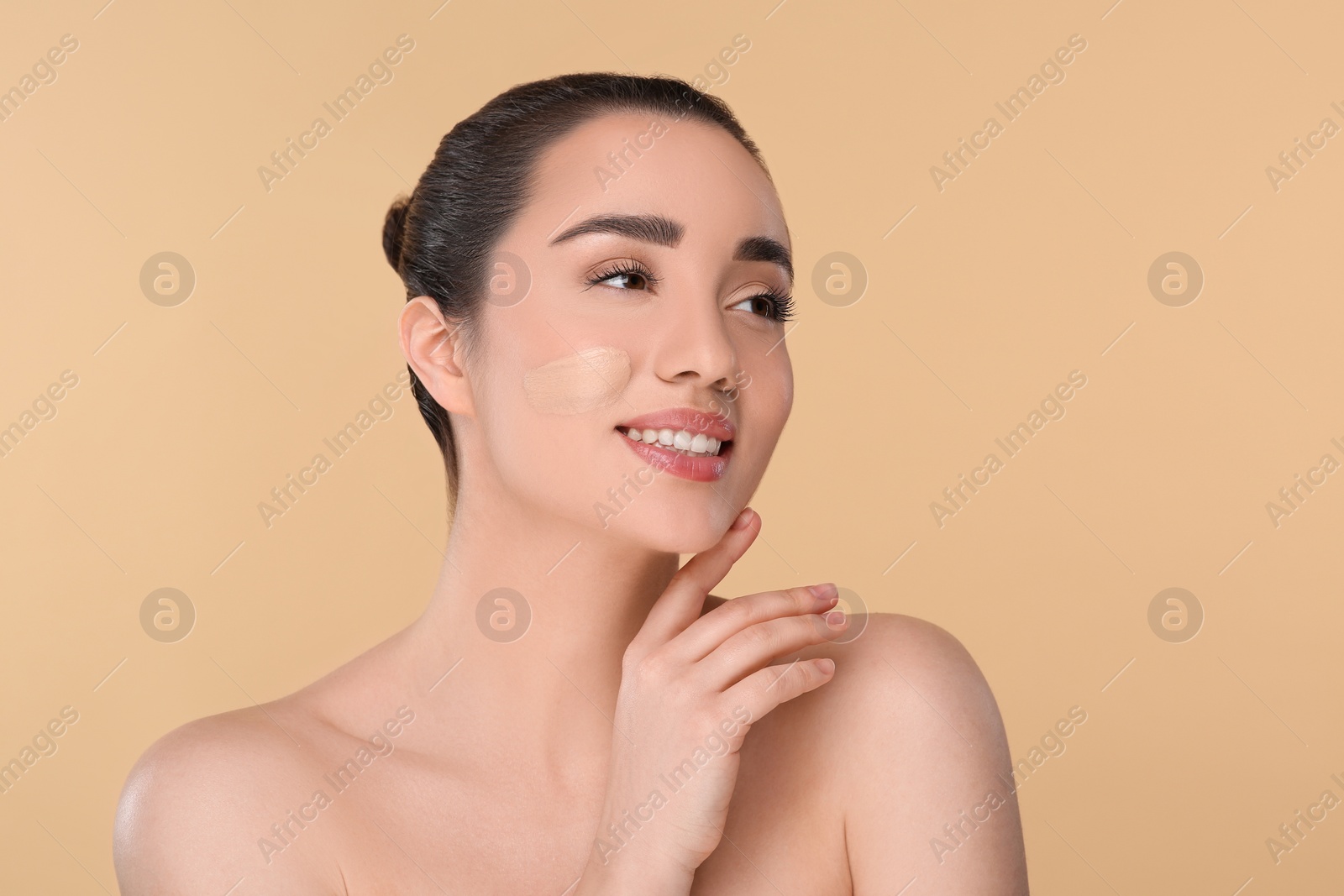 Photo of Woman with swatch of foundation on face against beige background