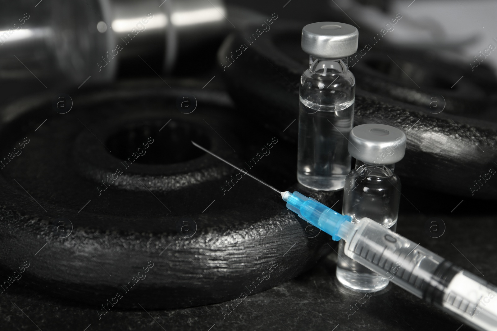 Photo of Vials and syringe with drug near sports equipment on table, closeup. Doping control