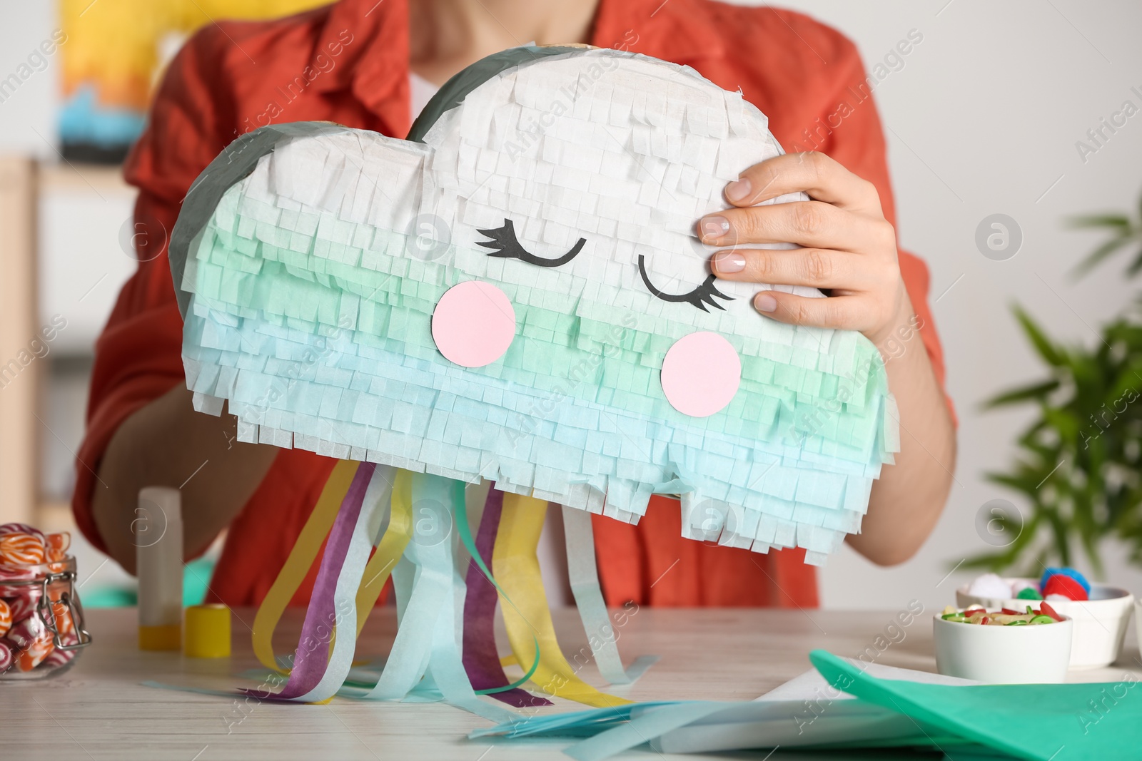 Photo of Woman making cardboard cloud at white wooden table, closeup. Pinata diy