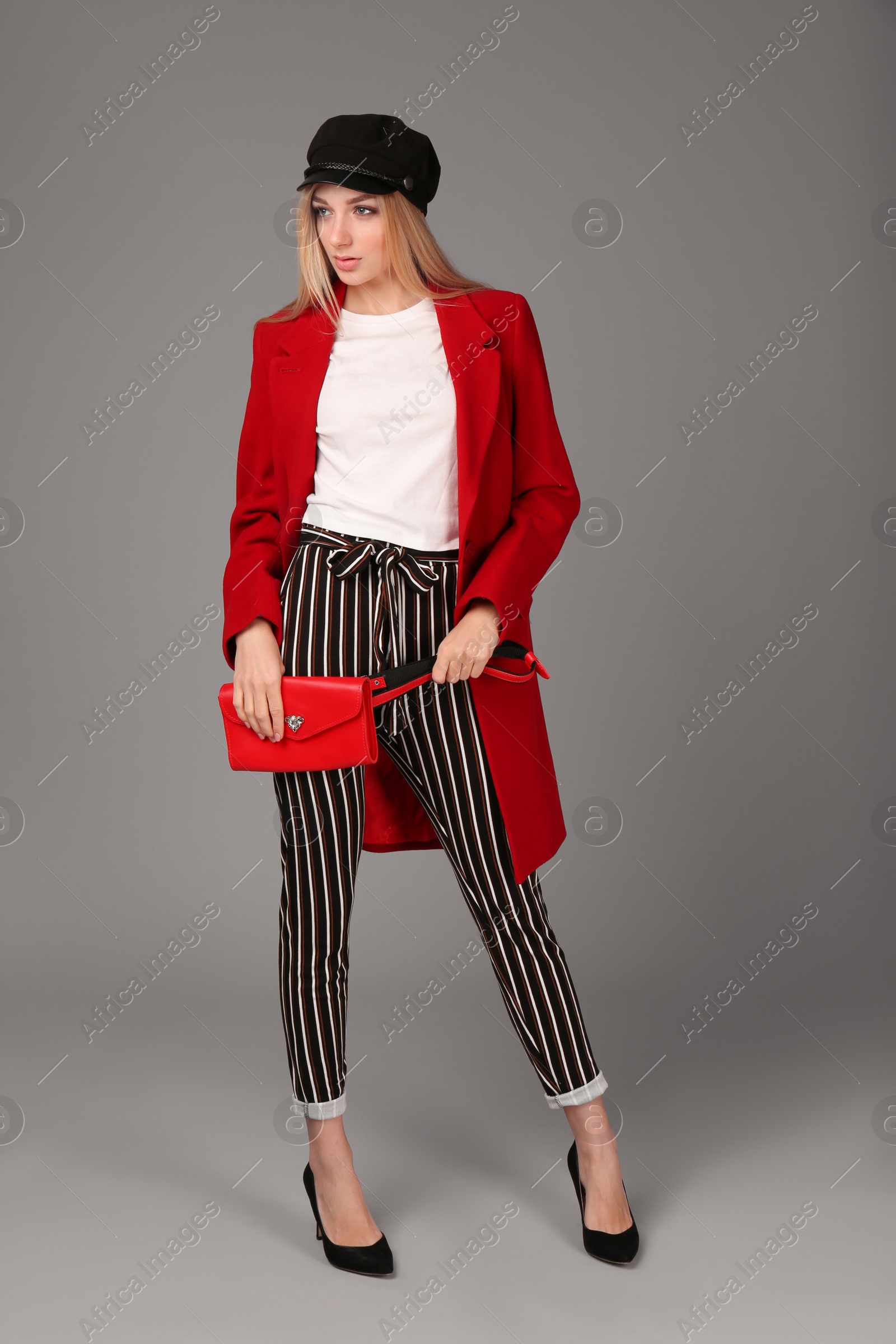 Photo of Young stylish woman in trendy shoes with bum bag on grey background