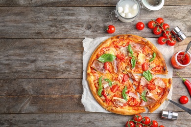 Photo of Delicious pizza with tomatoes and meat on wooden background