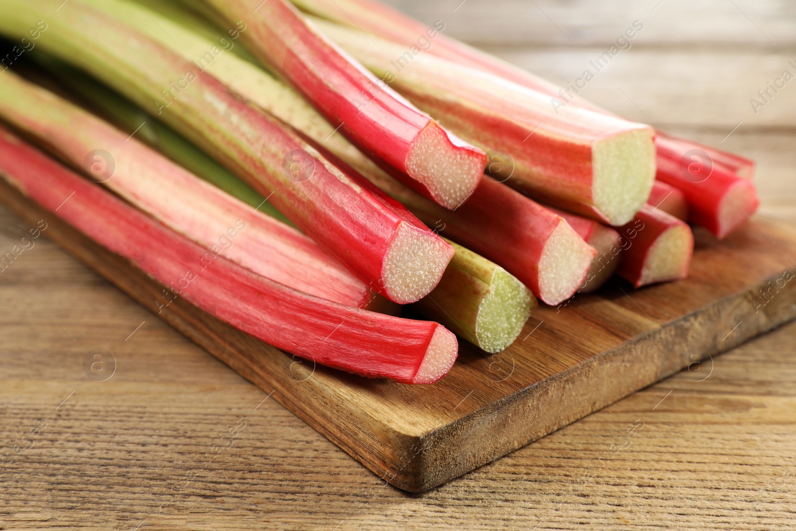 Photo of Many cut rhubarb stalks on wooden table, closeup