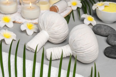 Spa bags, stones and orchid flowers on light gray table