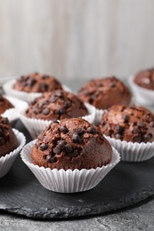 Photo of Tasty chocolate muffins on grey textured table, closeup. Space for text