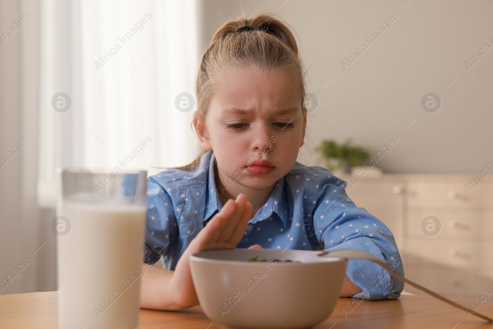 Photo of Cute little girl refusing to eat her breakfast at home