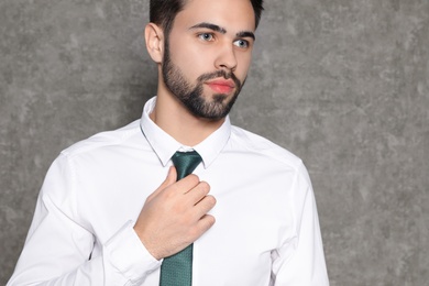 Photo of Portrait of businessman straightening tie on grey background, closeup