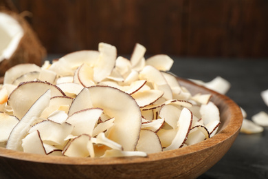 Photo of Tasty coconut chips in wooden bowl, closeup