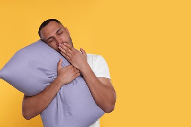 Tired man with pillow yawning on orange background, space for text. Insomnia problem