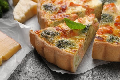 Photo of Delicious homemade quiche with salmon and broccoli on gray table, closeup