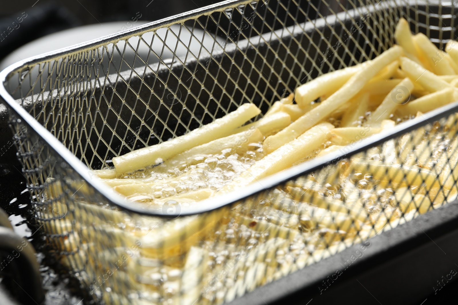 Photo of Cooking delicious french fries in hot oil, closeup