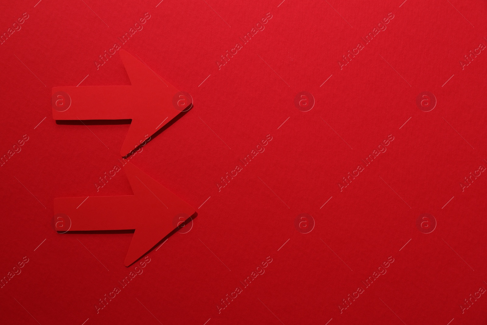 Photo of Paper arrows on red background, flat lay. Space for text