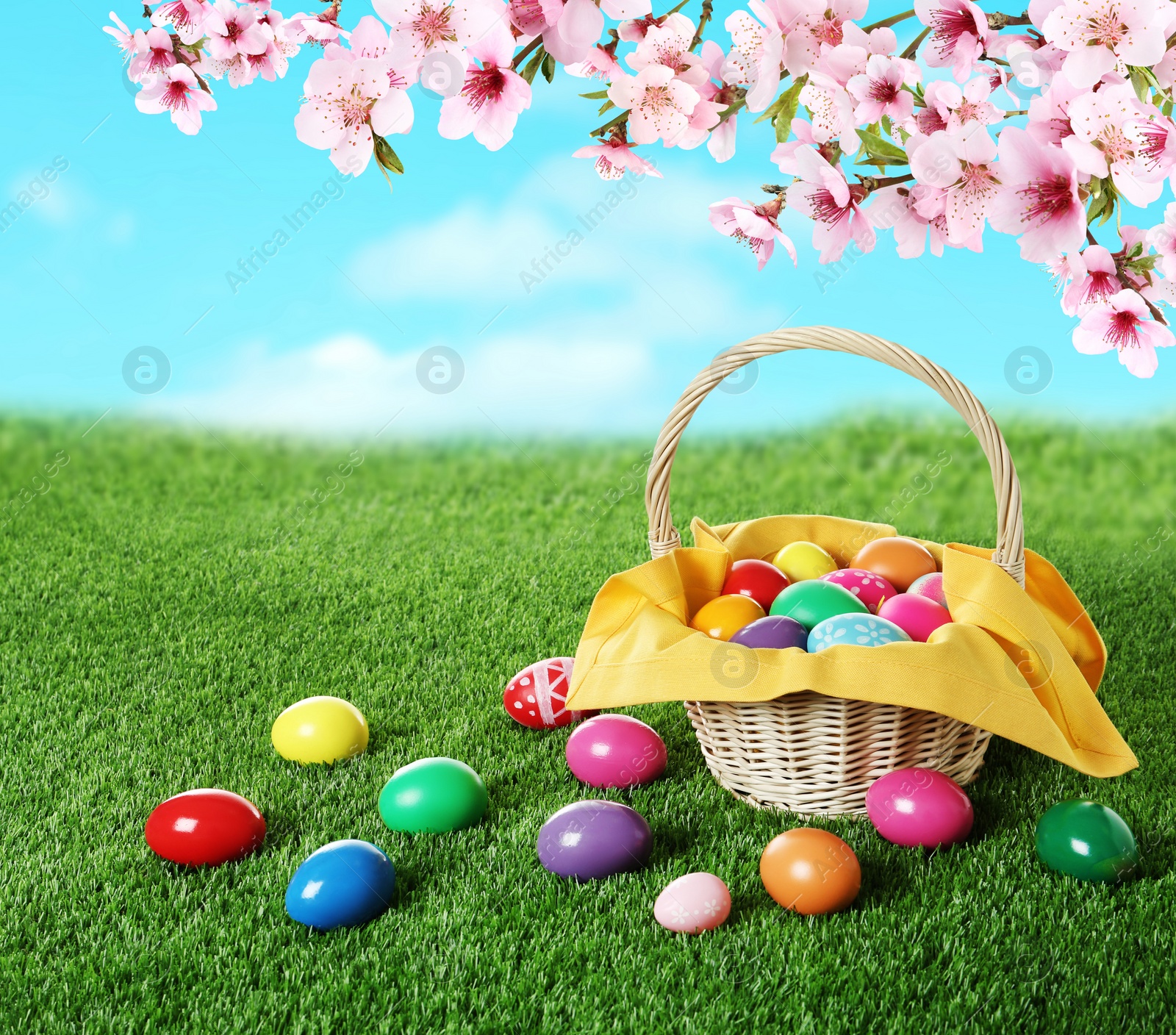 Image of Wicker basket with Easter eggs on green grass outdoors, space for text