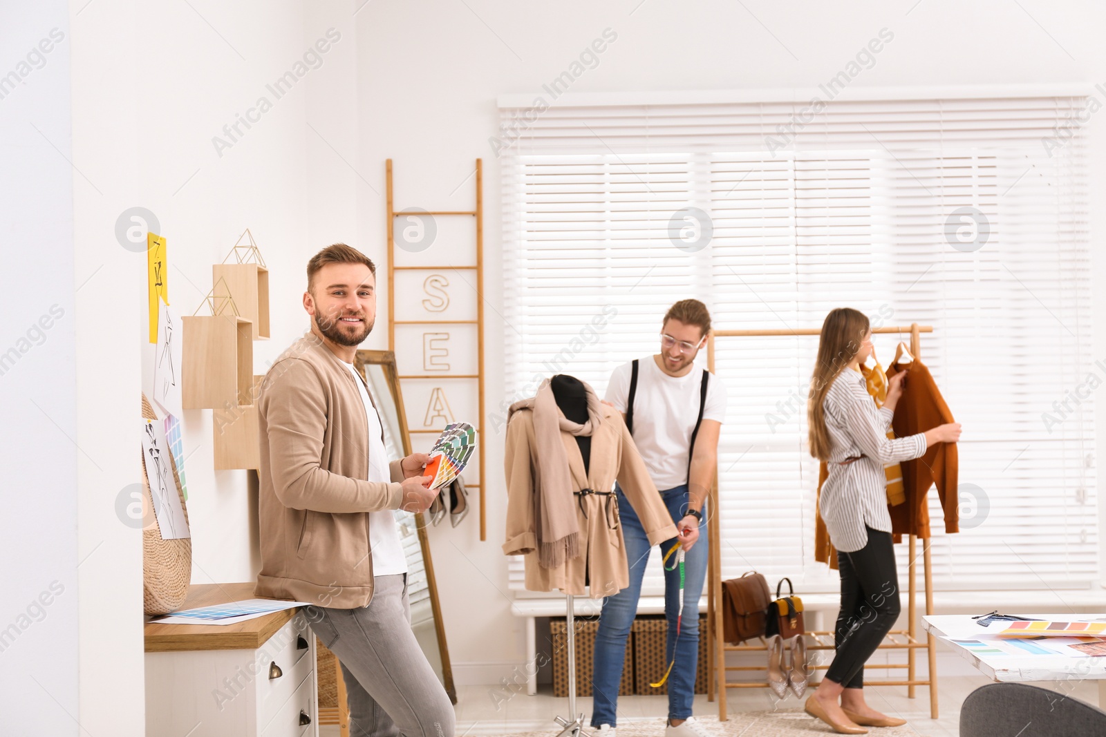 Photo of Fashion designer with colleagues creating new clothes in studio