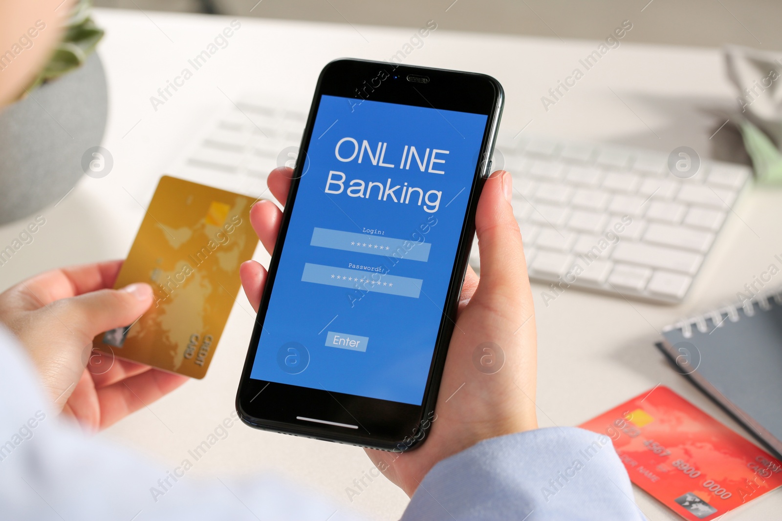 Photo of Woman using online banking app on smartphone and credit card at white office table, closeup