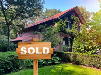 Image of Wooden Sold sign near beautiful house outdoors