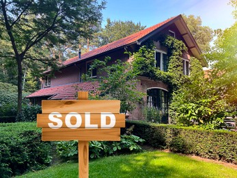 Wooden Sold sign near beautiful house outdoors