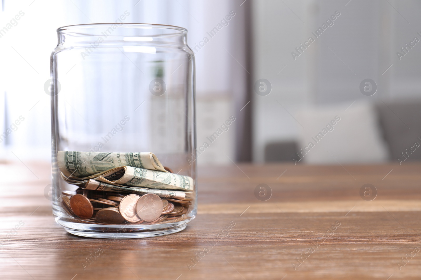 Photo of Donation jar with money on table against blurred background. Space for text