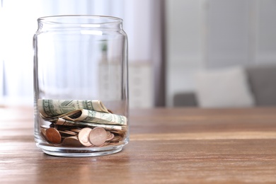 Donation jar with money on table against blurred background. Space for text