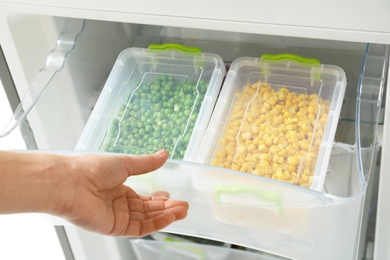 Photo of Woman opening refrigerator drawer with frozen vegetables, closeup