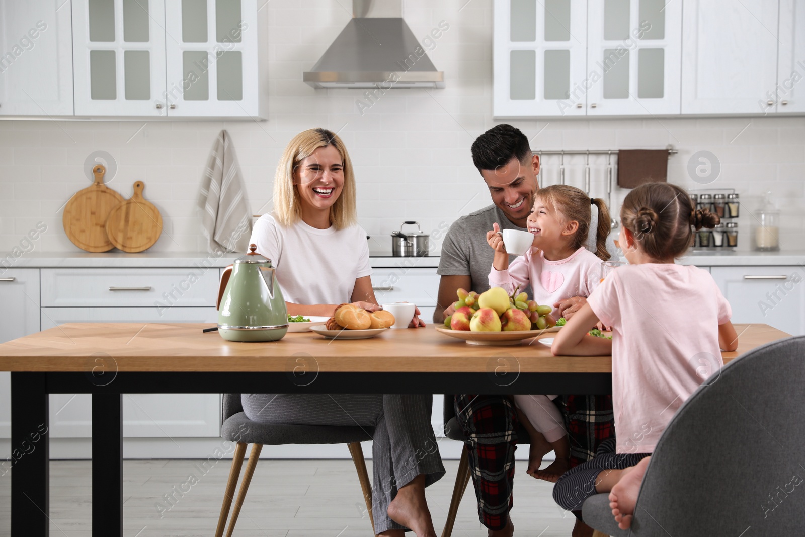 Photo of Happy family having breakfast together at table in modern kitchen