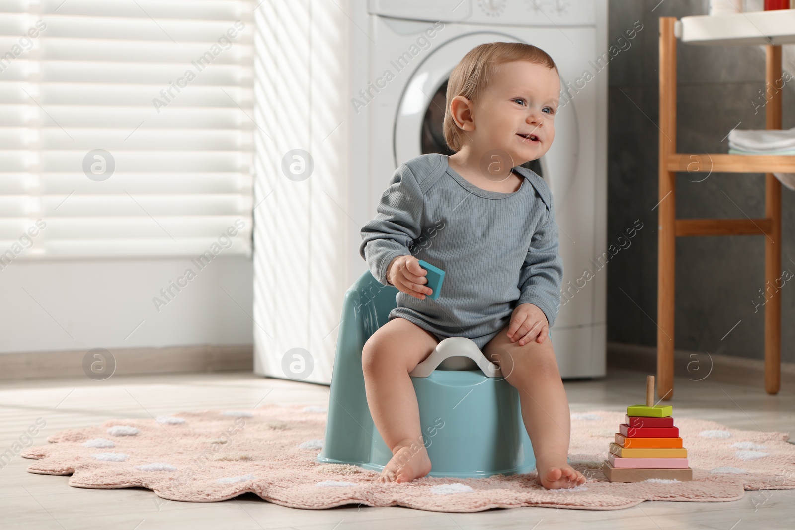 Photo of Little child sitting on plastic baby potty indoors. Space for text