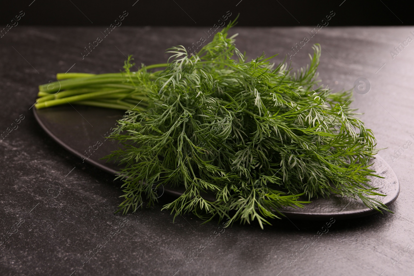 Photo of Sprigs of fresh dill on dark textured table, closeup