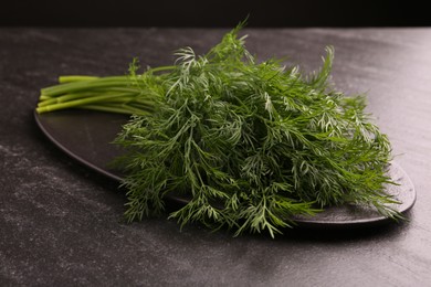 Photo of Sprigs of fresh dill on dark textured table, closeup