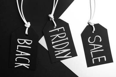 Tags with words BLACK FRIDAY SALE on color background, flat lay